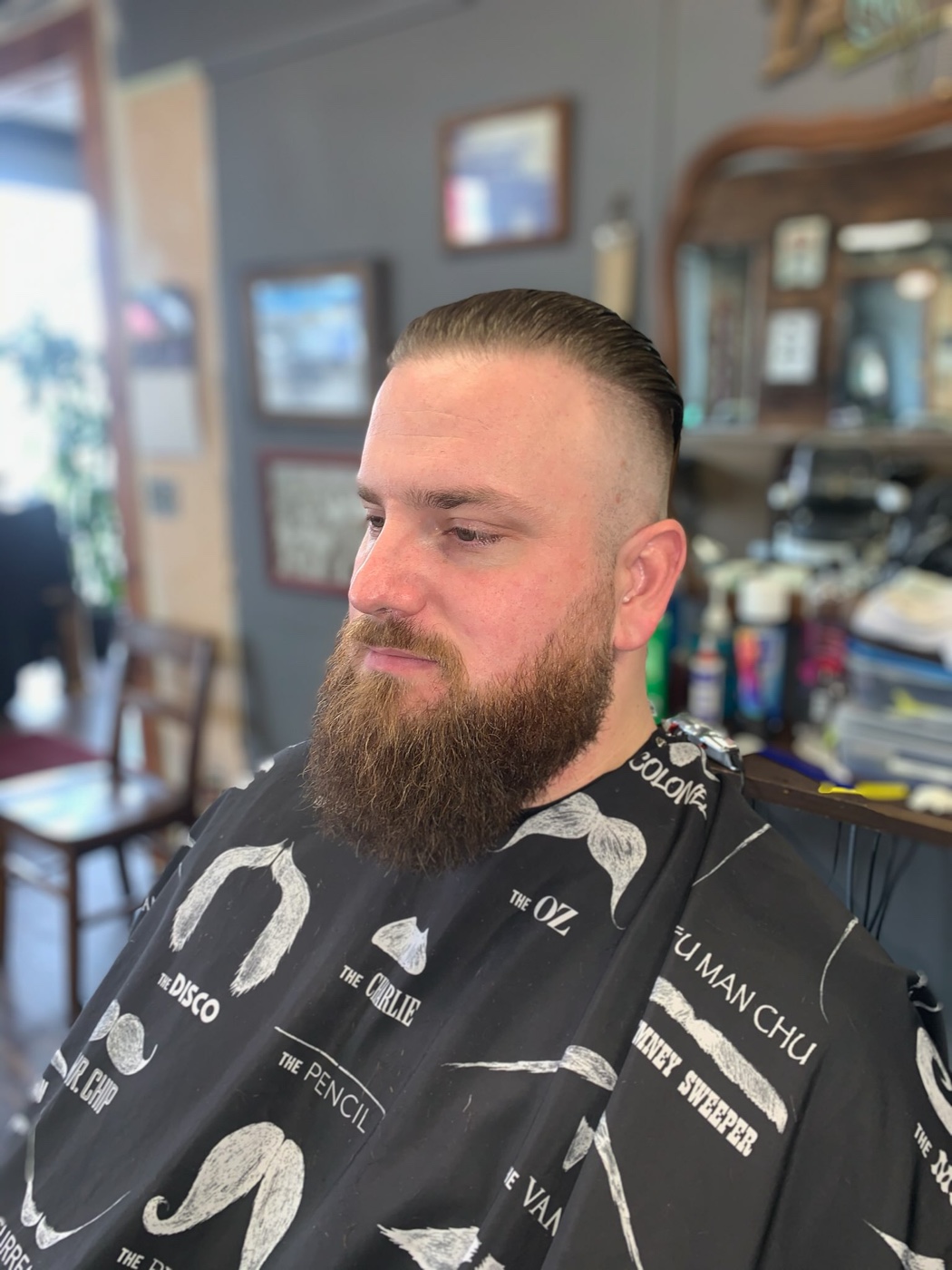 Men's slicked-back haircut and beard grooming at Truly Blessed Barber Studio